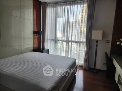 Modern bedroom with large window and city view, featuring sleek furniture and elegant decor.