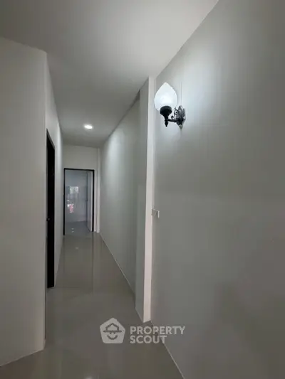 Sleek and modern hallway with polished floors and elegant wall sconce lighting.
