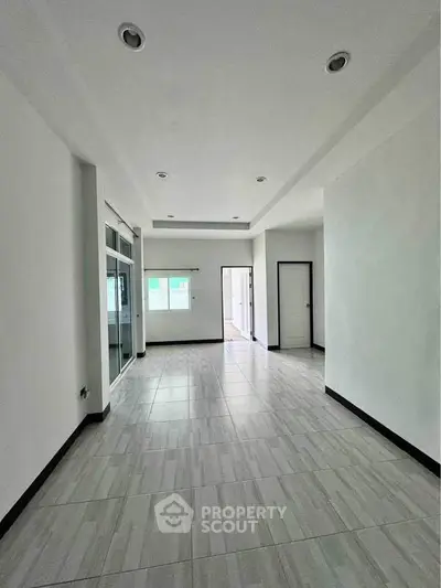 Spacious modern living room with sleek tile flooring and recessed lighting.