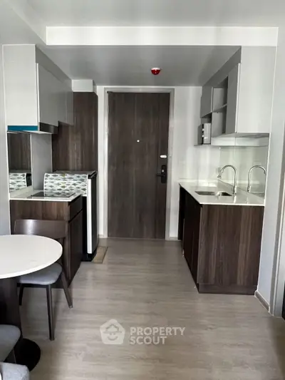 Modern kitchen with sleek cabinetry and dining area in compact apartment