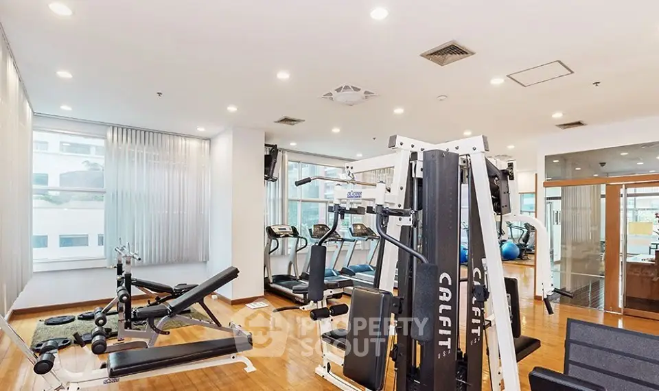 Spacious modern gym with state-of-the-art fitness equipment and bright natural lighting.