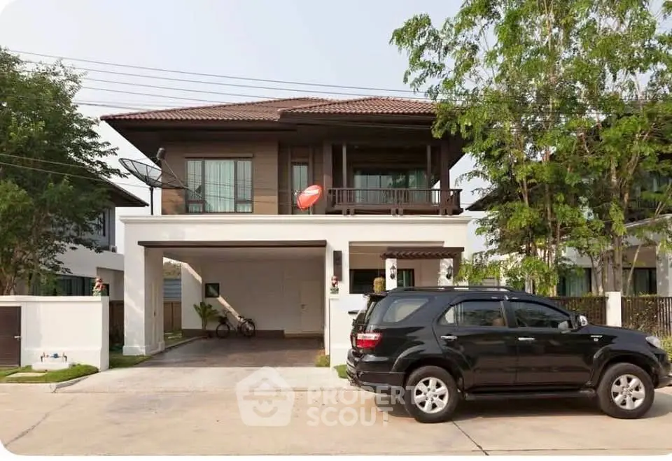 Charming two-story house with car parked in driveway, surrounded by lush greenery.