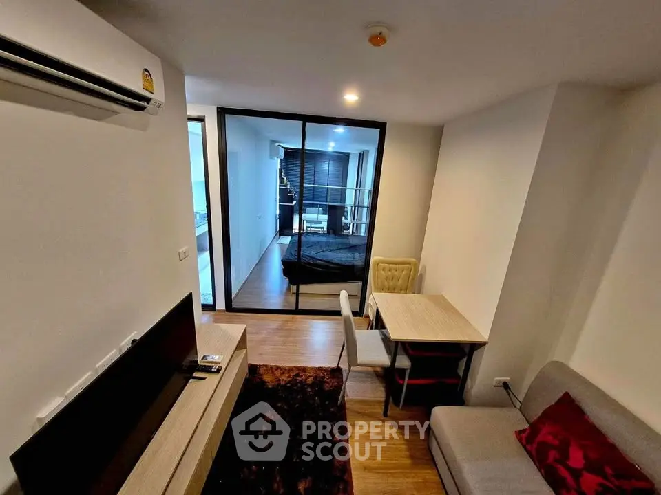 Modern living room with cozy seating and dining area, featuring a view into a stylish bedroom.