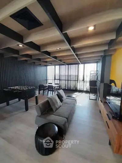 Modern living room with stylish ceiling and foosball table, perfect for entertainment.