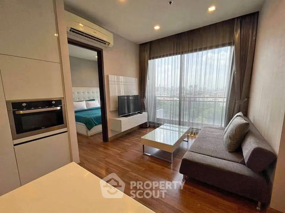 Modern living room with city view, sleek furniture, and open layout adjacent to bedroom.