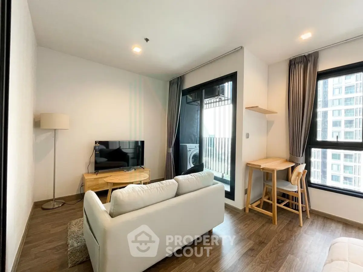 Modern living room with cozy seating and large windows in a stylish apartment.