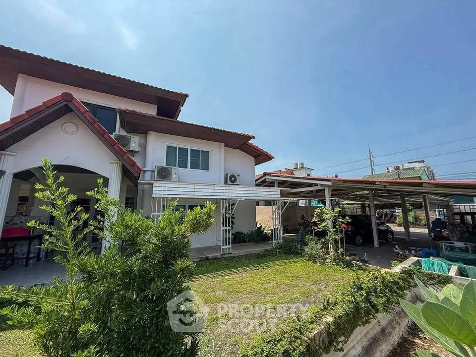 Charming two-story house with lush garden and carport in a serene neighborhood.