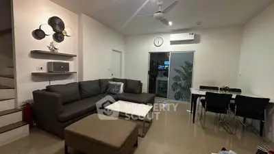Modern living room with sleek furniture and dining area, featuring neutral tones and contemporary decor.