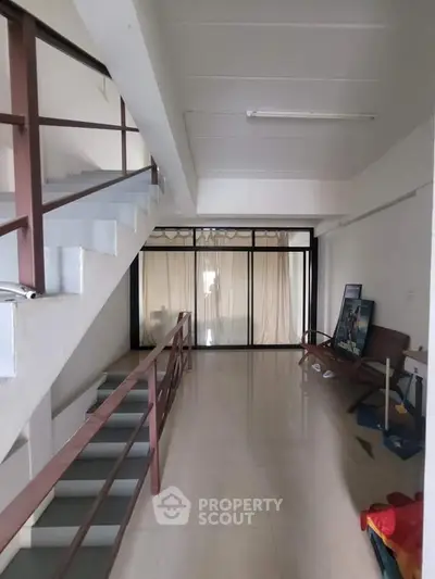 Spacious interior hallway with modern staircase and large window, ideal for creative design opportunities.