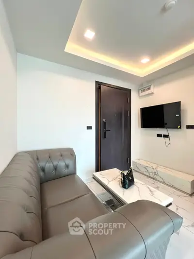 Modern living room with sleek sofa and wall-mounted TV, featuring elegant marble coffee table.