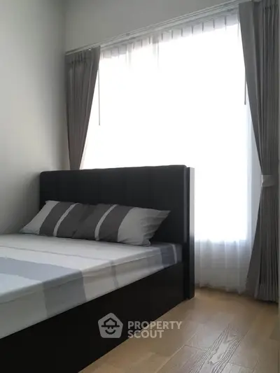 Modern bedroom with stylish bed and large windows offering natural light.