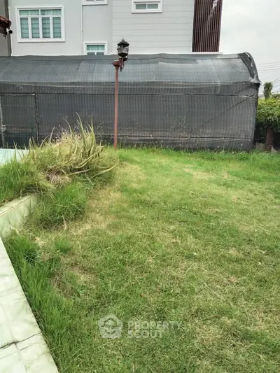 Spacious backyard with lush green lawn and modern building exterior.