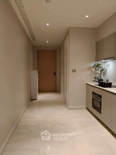 Modern kitchen with sleek cabinetry and built-in oven in a minimalist apartment.