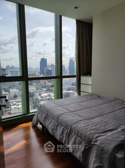 Modern bedroom with stunning city view and floor-to-ceiling windows in high-rise apartment.