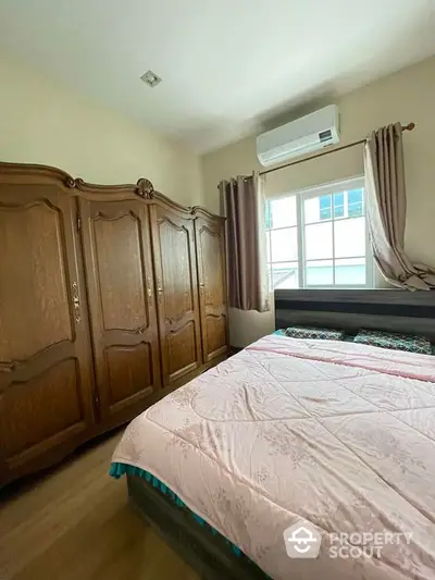 Cozy bedroom with large wooden wardrobe and air conditioning