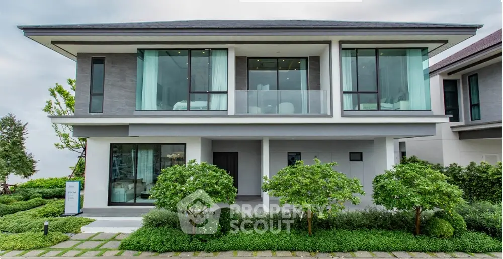 Modern two-story house with large windows and lush landscaping