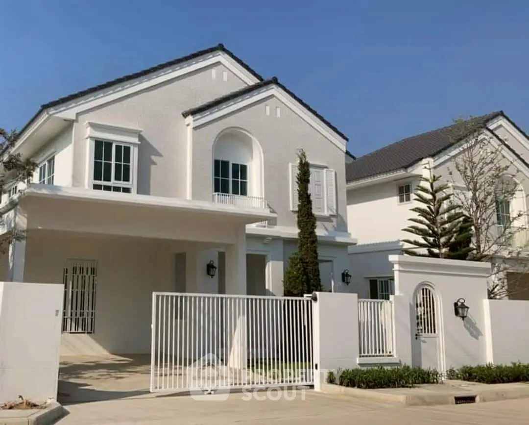 Elegant white two-story house with gated entrance and manicured landscaping