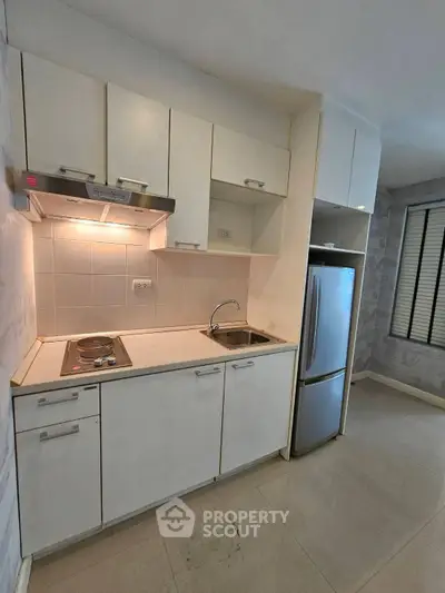 Modern compact kitchen with sleek cabinetry and stainless steel appliances in a stylish apartment.