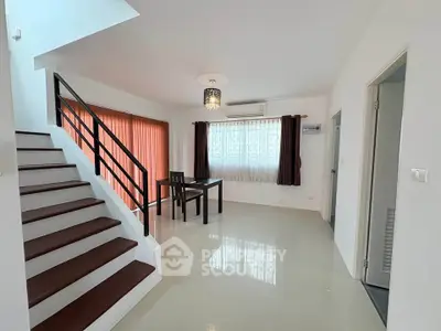Spacious modern living room with staircase and dining area, featuring sleek design and ample natural light.
