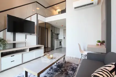 Modern living room with mezzanine, sleek furniture, and open kitchen layout in stylish apartment.