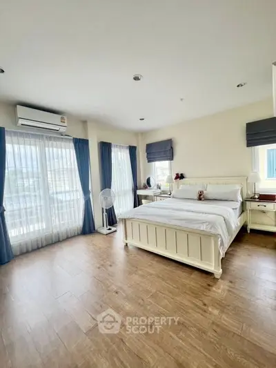 Spacious bedroom with elegant decor and large windows for natural light.