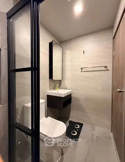 Modern bathroom with sleek design, featuring a glass shower partition and contemporary fixtures.