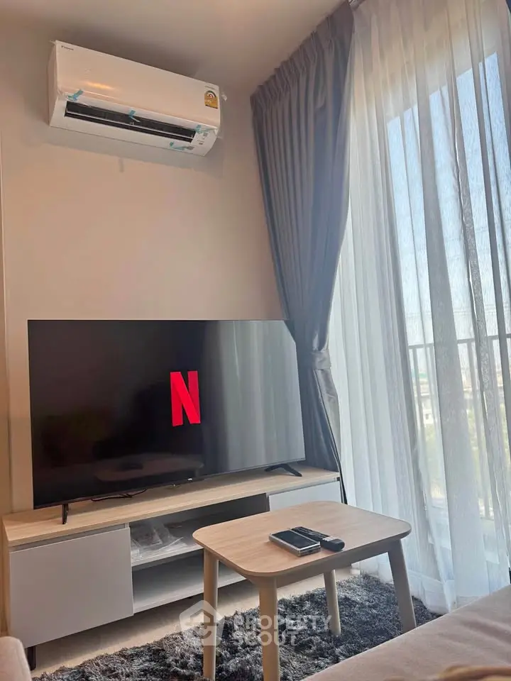 Cozy living room with modern TV setup and air conditioning, perfect for relaxation.