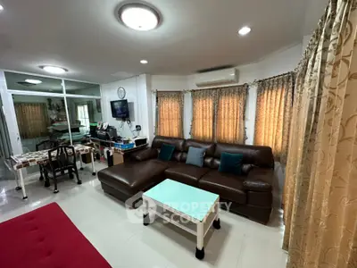 Spacious living room with leather sofa and elegant curtains, perfect for family gatherings.
