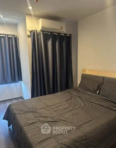 Cozy bedroom with modern decor and air conditioning, featuring dark curtains and bedding for a restful ambiance.