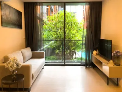 Modern living room with large window overlooking lush garden, featuring cozy sofa and sleek TV stand.