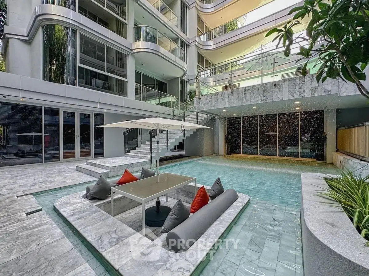 Luxurious modern building with stunning poolside seating area and elegant architecture.