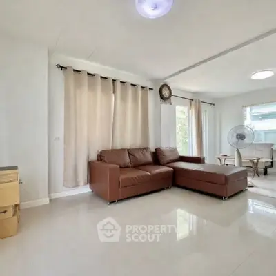 Spacious living room with modern brown leather sofa and natural light