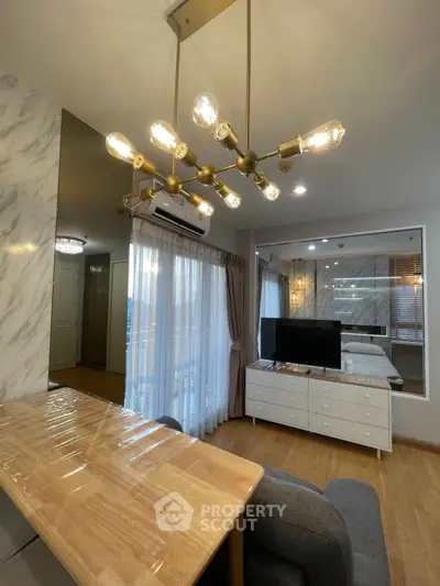 Modern studio apartment with stylish lighting and cozy furnishings, featuring a mirrored wall and natural light.