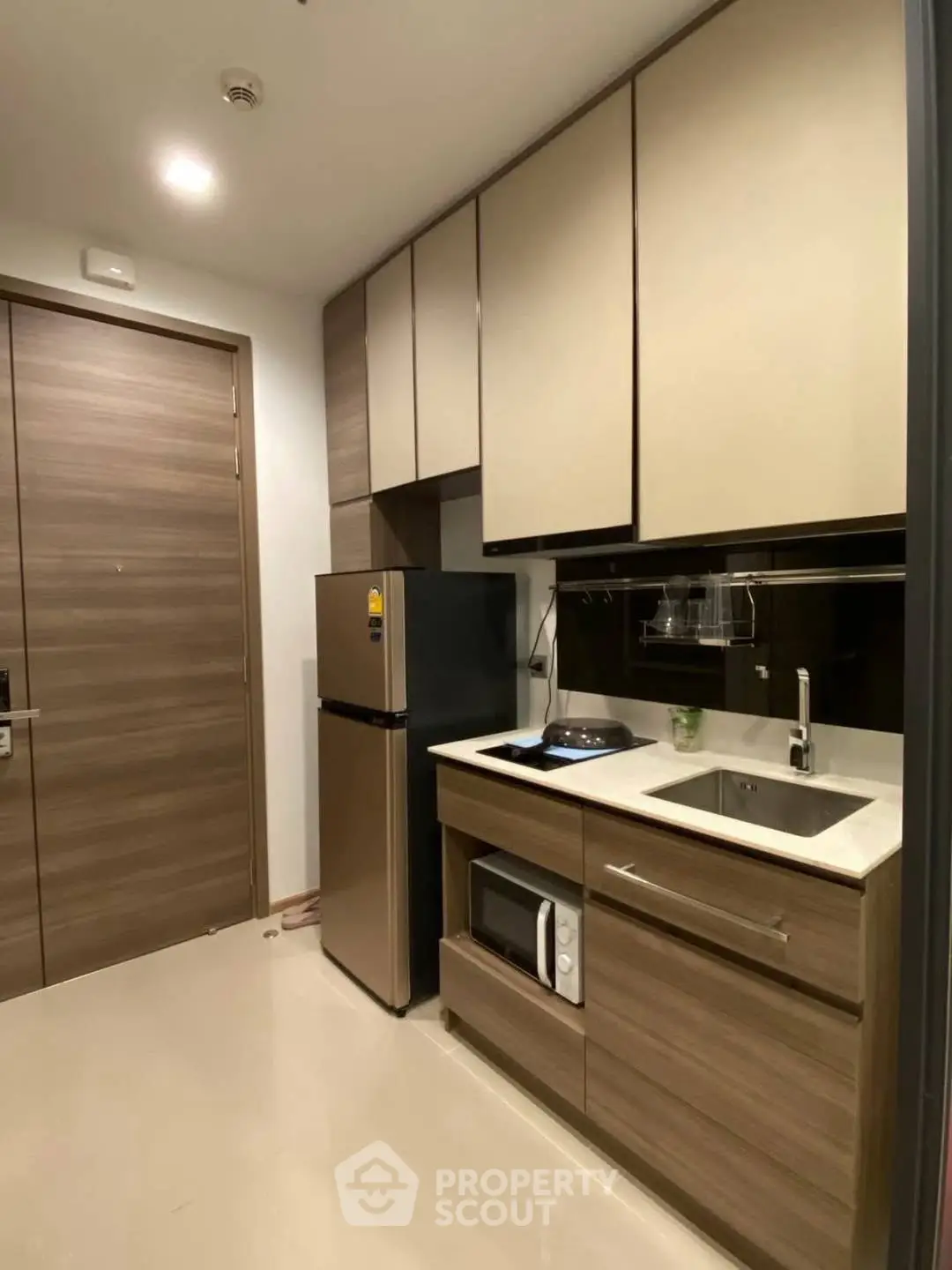 Modern compact kitchen with sleek cabinetry and stainless steel appliances in a stylish apartment.
