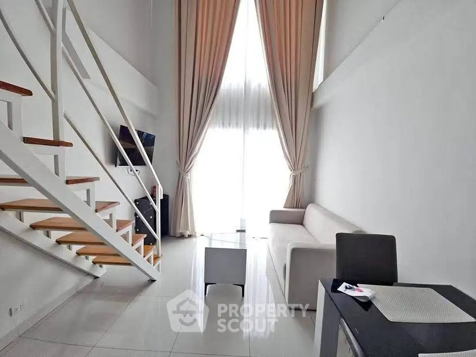 Modern loft-style living room with high ceilings and elegant staircase