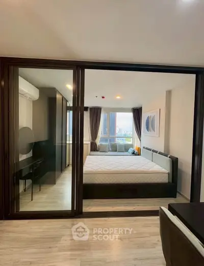 Modern bedroom with glass partition and stylish decor in urban apartment.