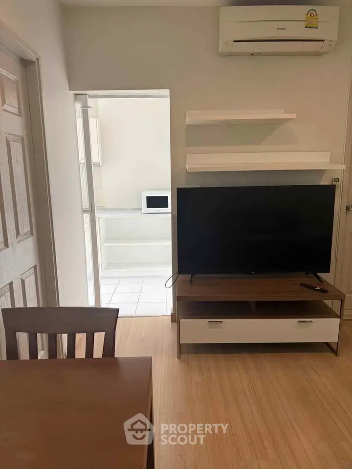 Modern living room with TV, air conditioning, and dining area in a cozy apartment.