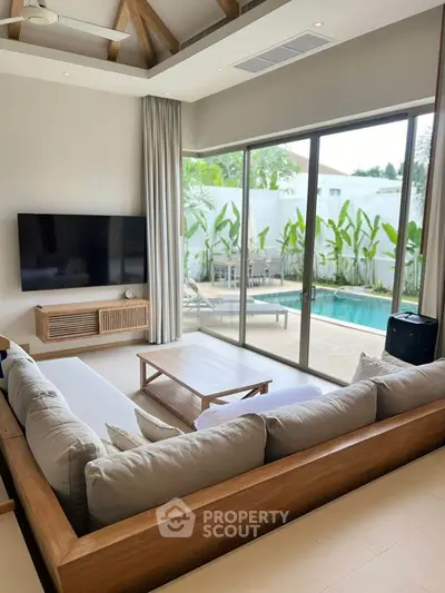 Luxurious living room with pool view, modern decor and large TV, perfect for relaxation.