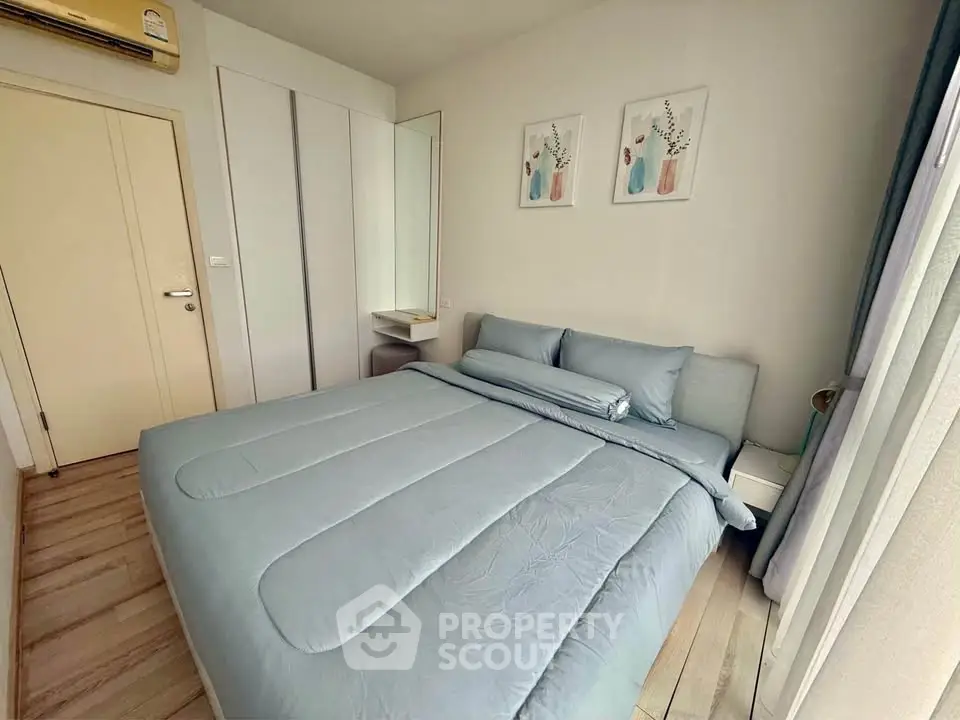 Cozy bedroom with modern decor and ample natural light, featuring a comfortable bed and stylish artwork.
