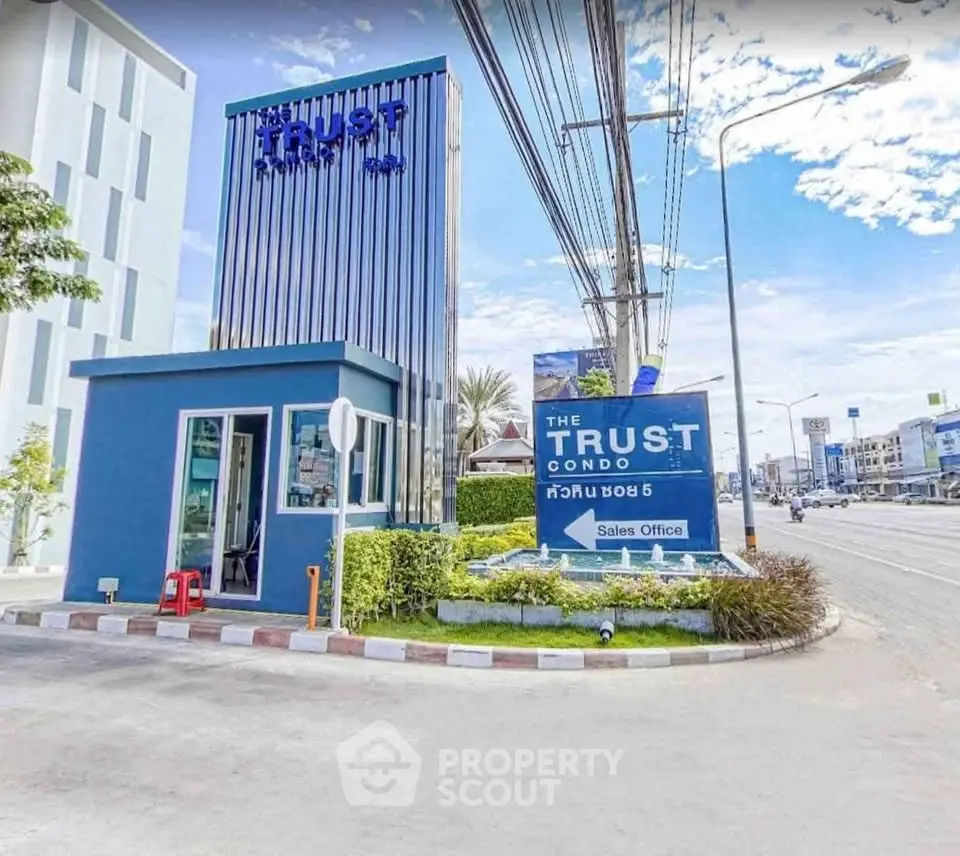 Modern condo sales office with striking blue facade and prominent signage on a sunny day.