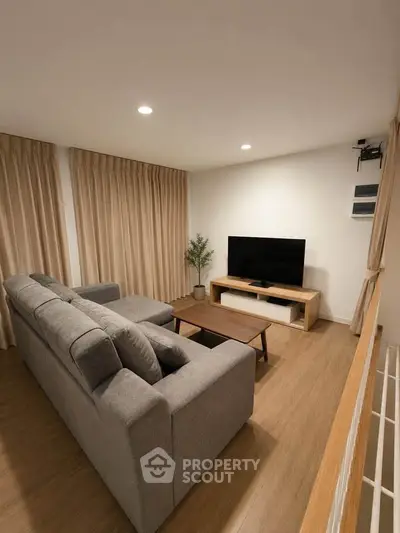 Modern living room with cozy gray sofa and flat-screen TV, perfect for relaxation.