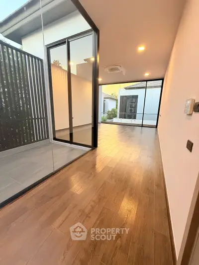 Modern interior with wooden flooring and large glass doors leading to a private outdoor space.