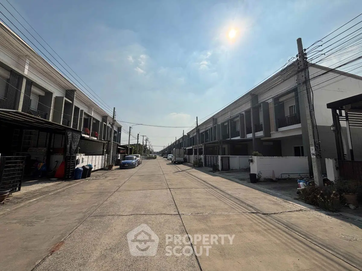 Modern townhouse complex with clear blue sky and sunlit street view.