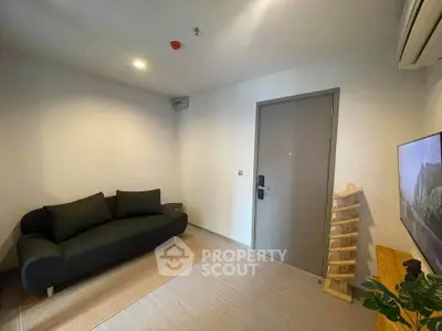 Modern living room with sleek black sofa and wall-mounted TV in a minimalist apartment.