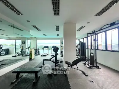 Spacious gym with modern equipment and large windows offering scenic views.