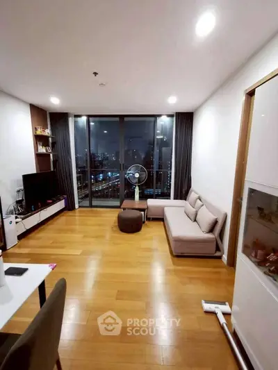 Modern living room with city view, wooden flooring, and sleek furniture.