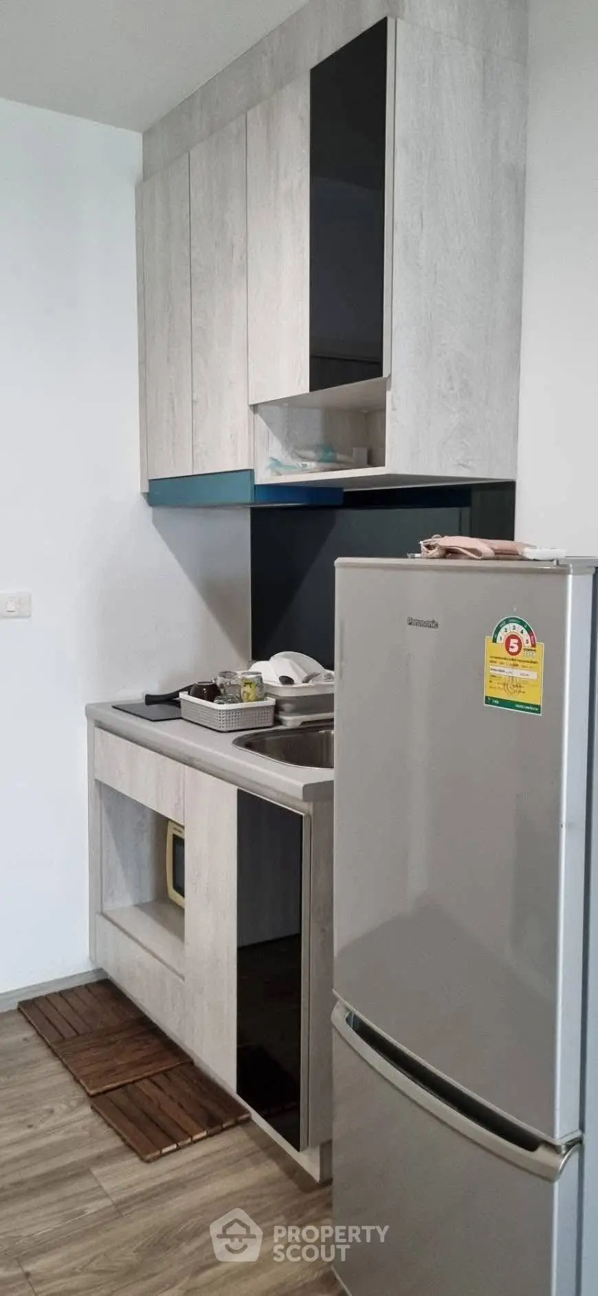 Modern kitchen with sleek cabinetry and stainless steel fridge in a compact layout.