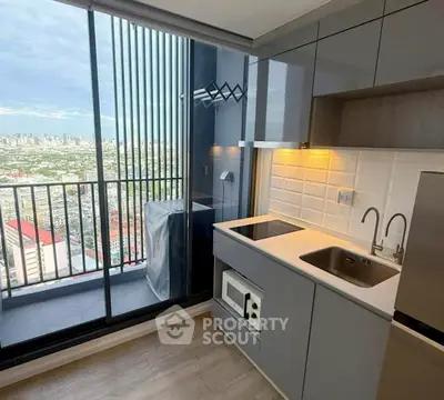 Modern kitchen with city view from high-rise balcony, featuring sleek cabinetry and appliances.