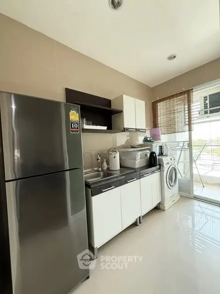 Modern kitchen with stainless steel fridge and washing machine, bright and airy space.