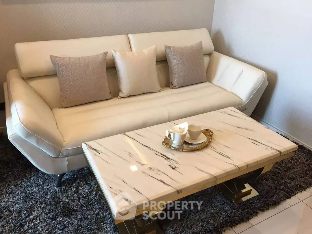 Luxurious living room with elegant white sofa and marble coffee table on plush rug.